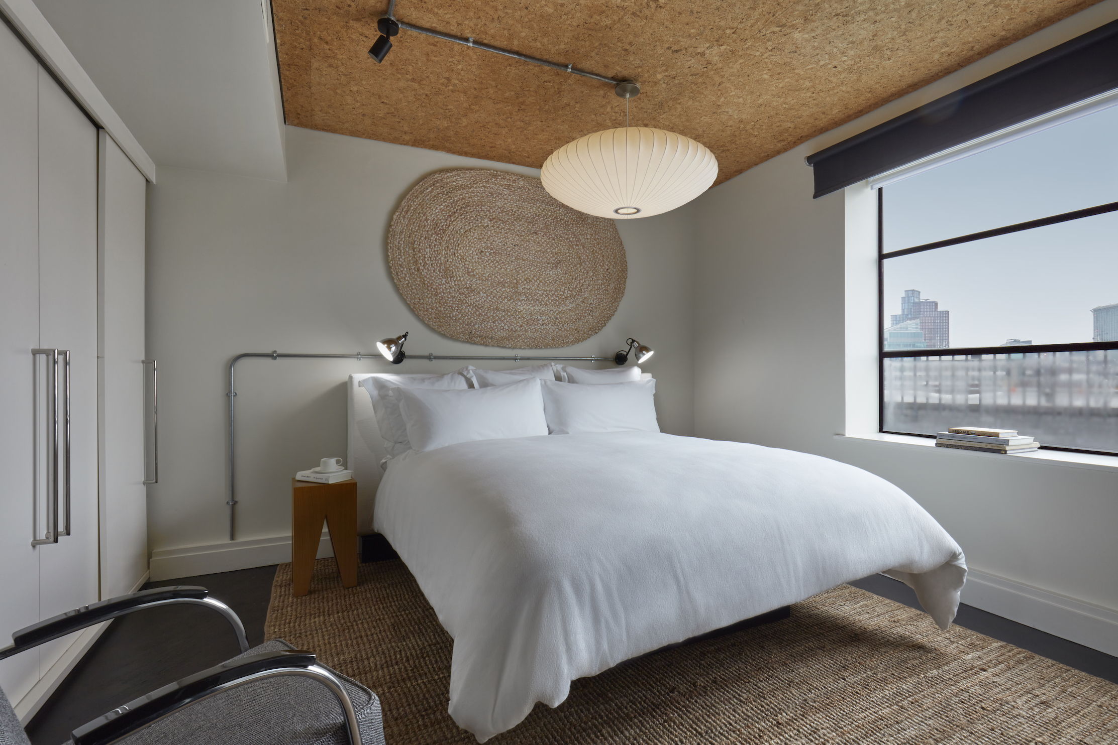 A serene bedroom featuring a white bed positioned near a window, allowing natural light to illuminate the space.