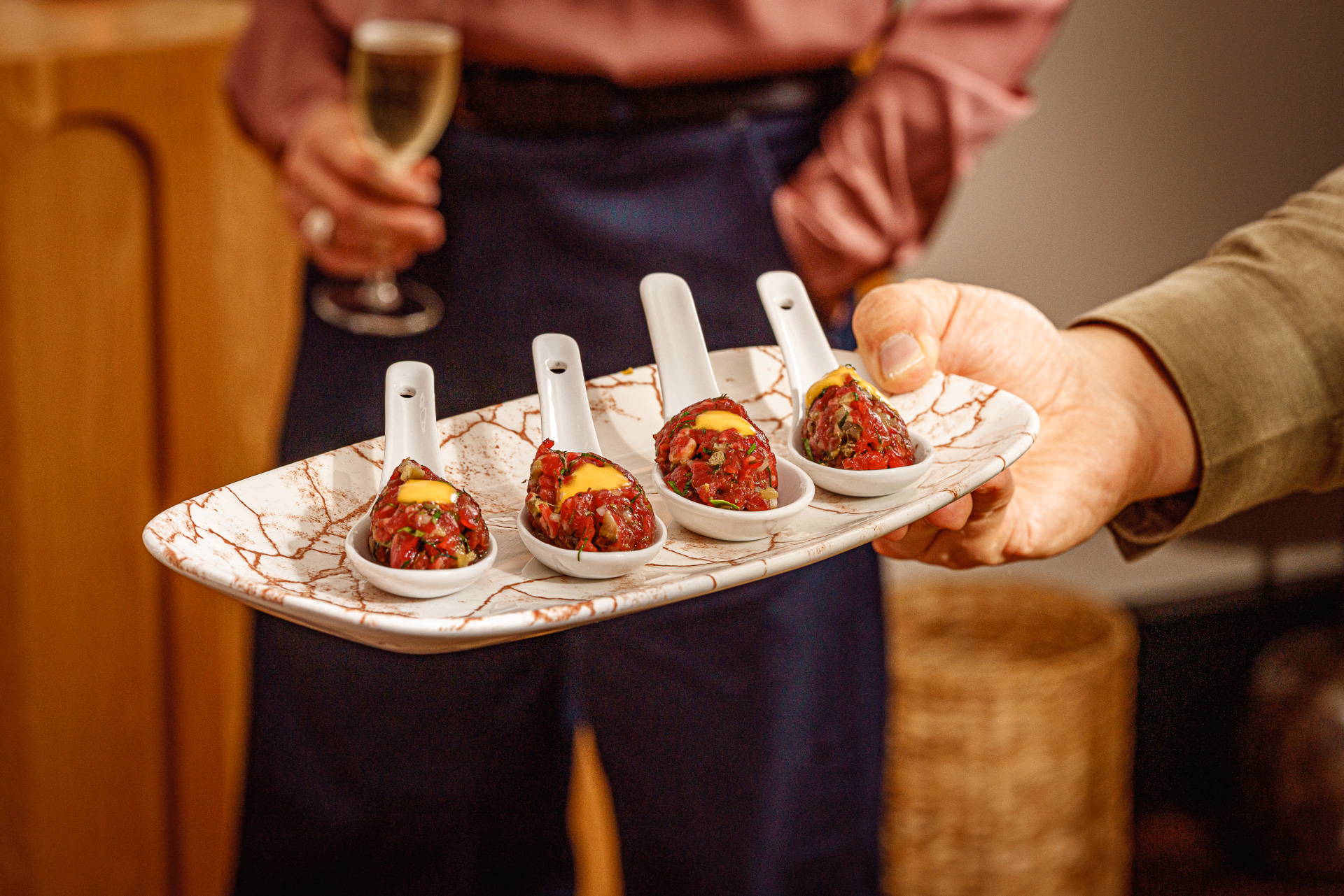 Four appetisers on porcelain spoons, garnished with a yellow sauce, served on a marbled tray at a London restaurant.