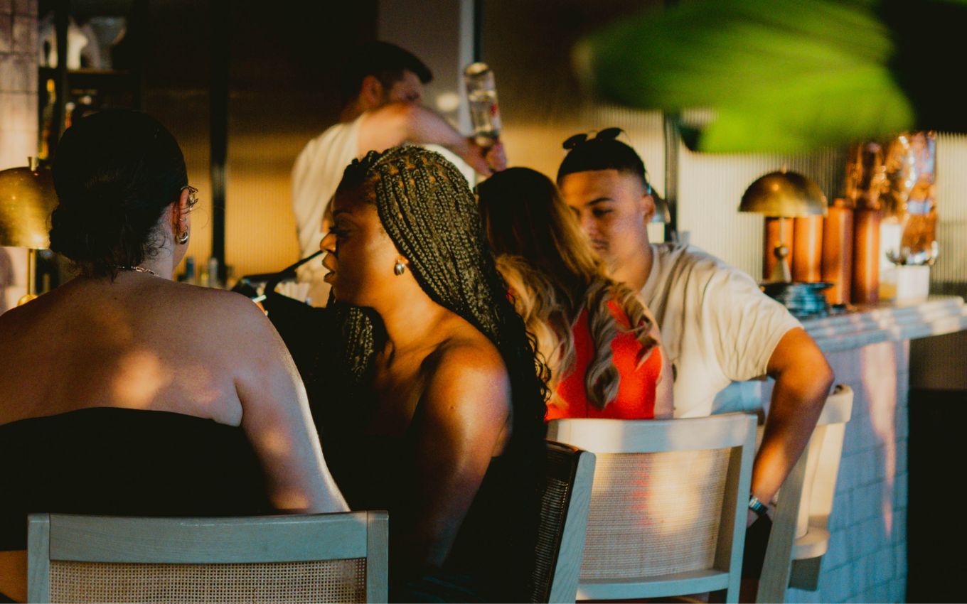 Group of people enjoying drinks at a bar in London with the sun shining into the place.