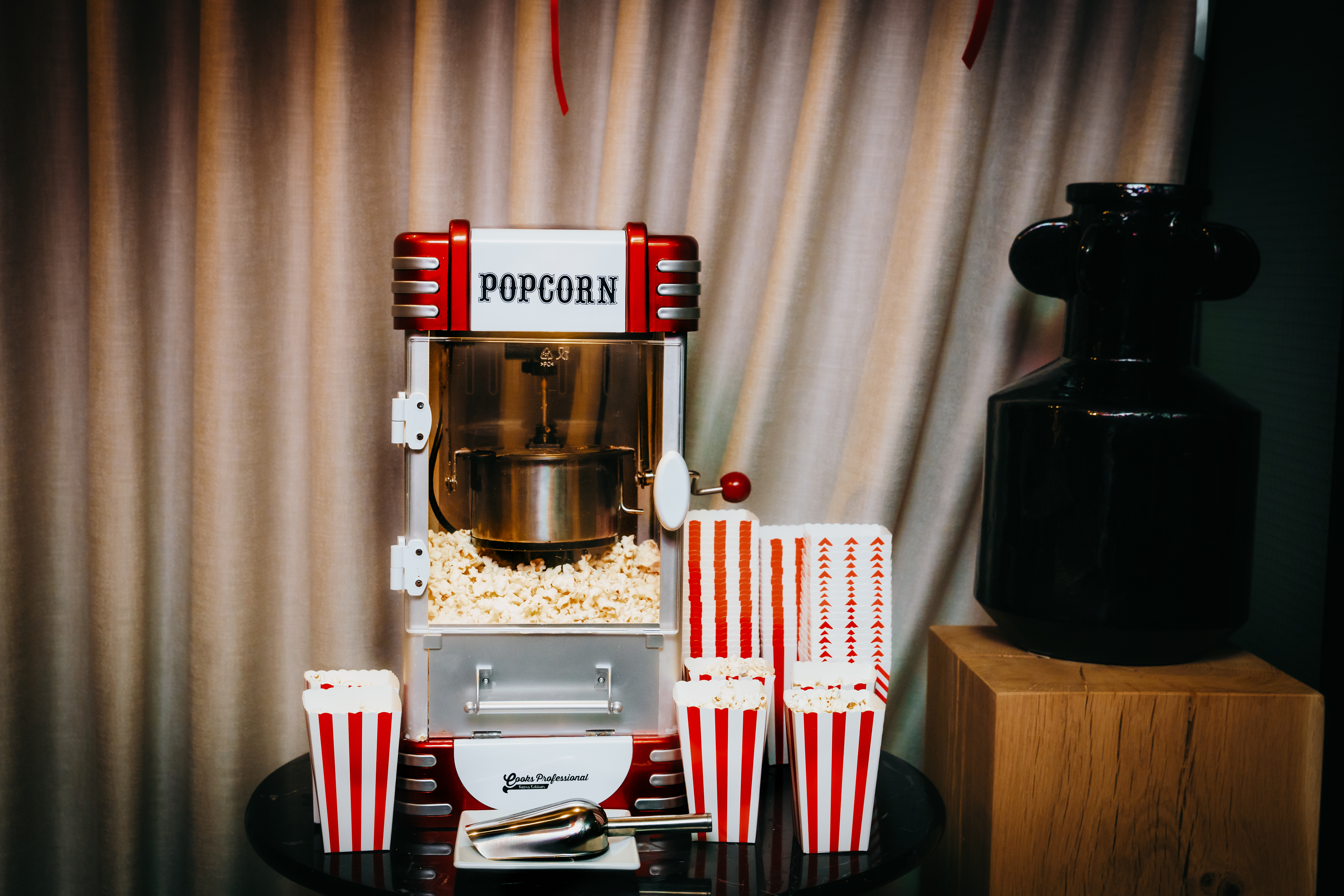 Classic popcorn machine with red and white striped boxes and fresh popcorn, set against a curtain at Curzon Cinema in London.