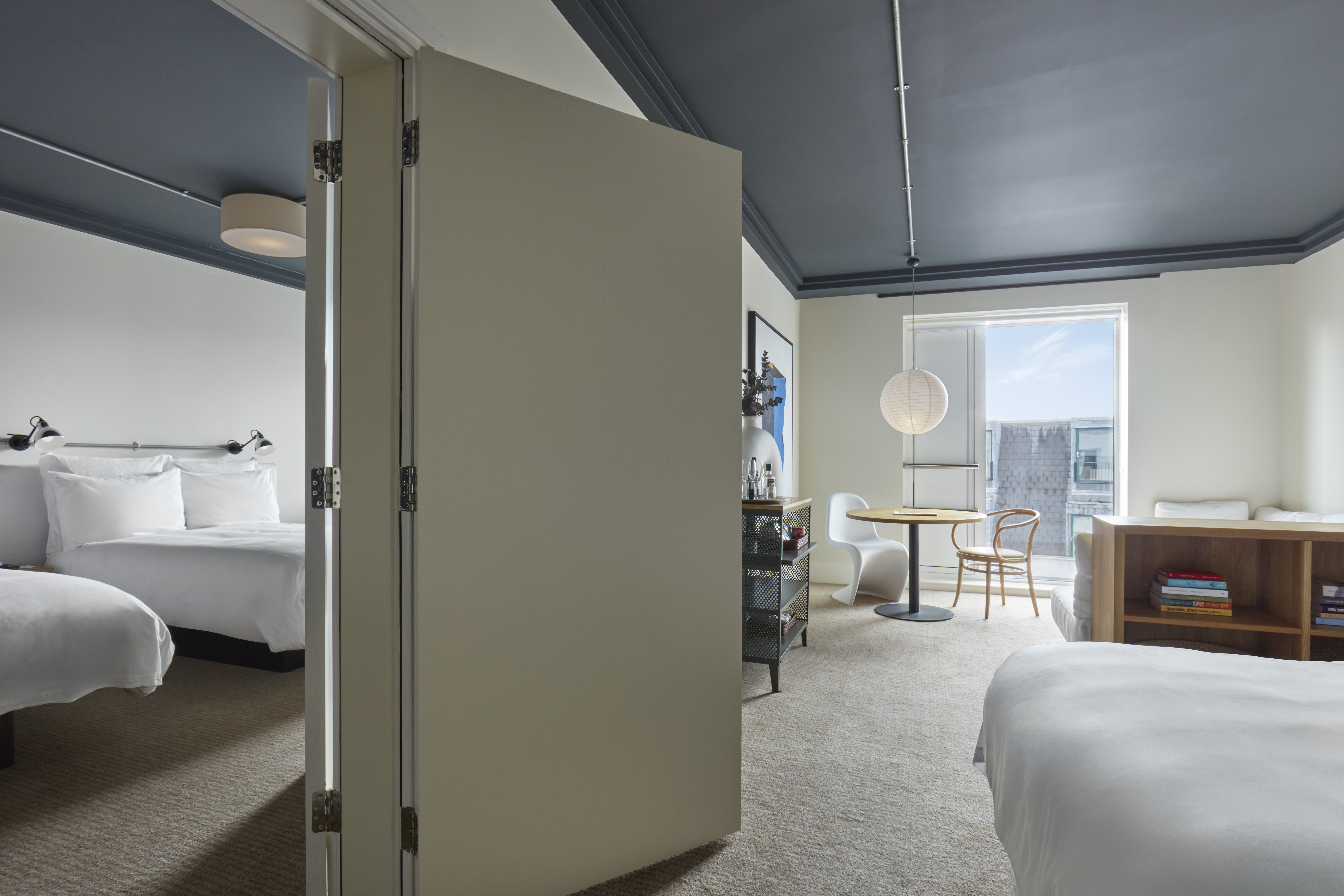 Spacious suite at One Hundred Shoreditch with an adjoining sitting and bedroom area, decorated in minimalist style.