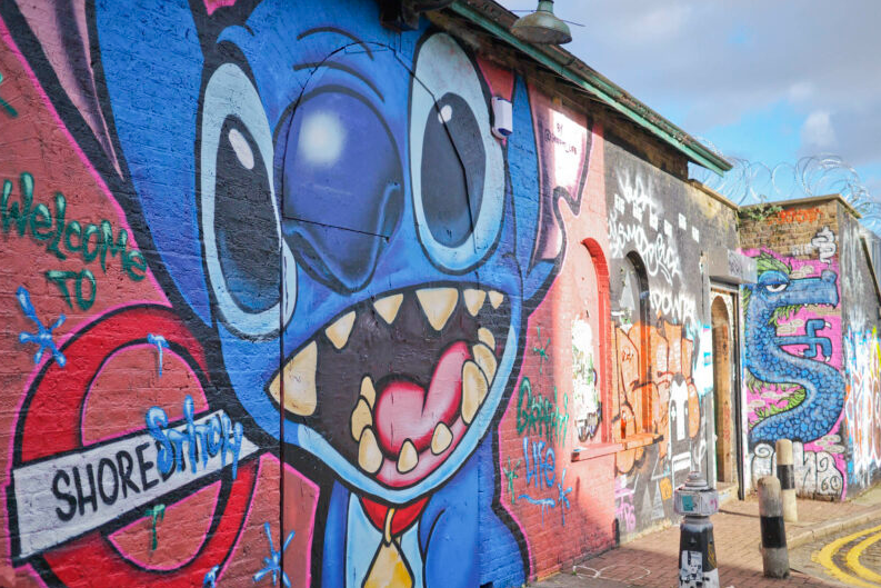 A colorful mural in Shoreditch featuring a graffiti-style illustration of Stitch with the text “Welcome to Shoreditch.”
