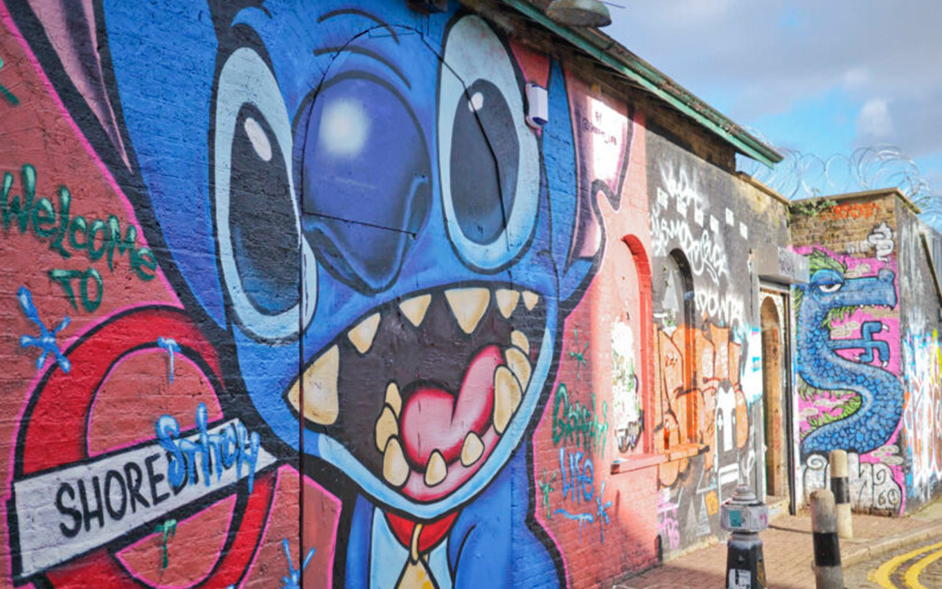 A colorful mural in Shoreditch featuring a graffiti-style illustration of Stitch with the text “Welcome to Shoreditch.”