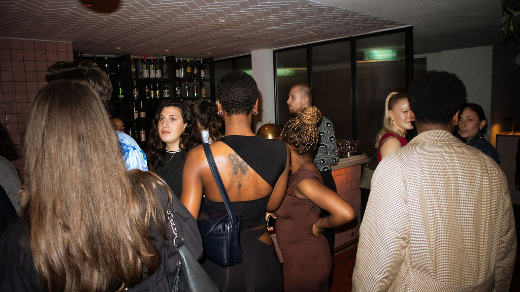 A diverse group of individuals socializing and enjoying drinks together in a lively bar setting.