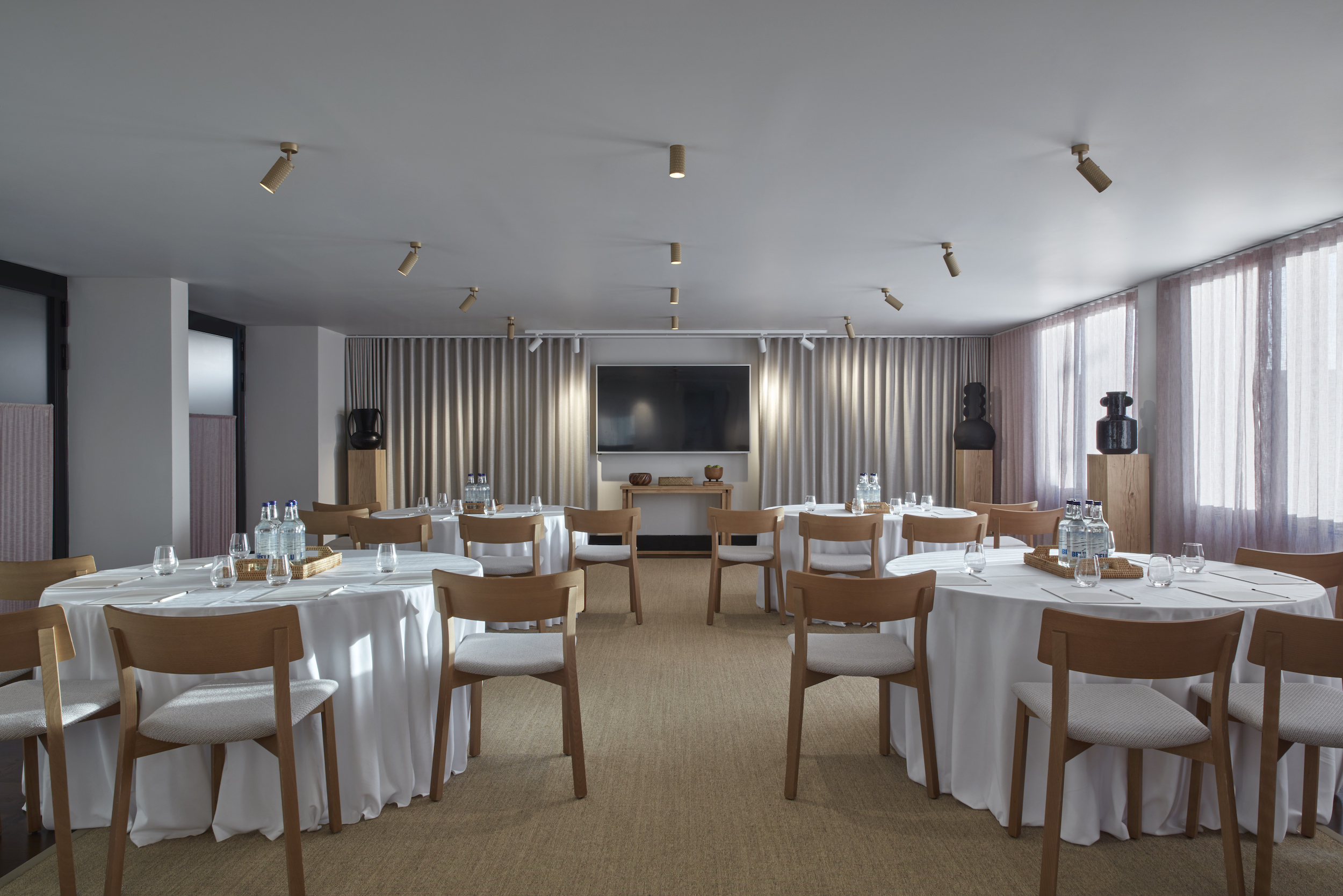 A stylish dining area with a long wooden table set for a meal, surrounded by elegant chairs and warm lighting.