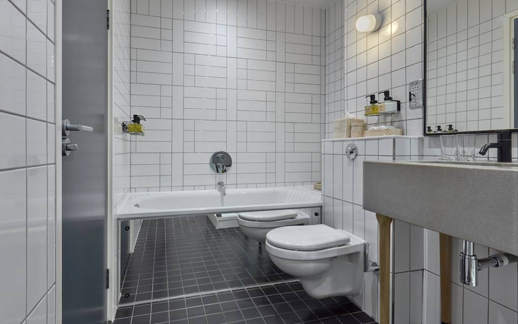 A modern bathroom featuring sleek white tiles and contrasting black flooring, creating a stylish and elegant atmosphere.