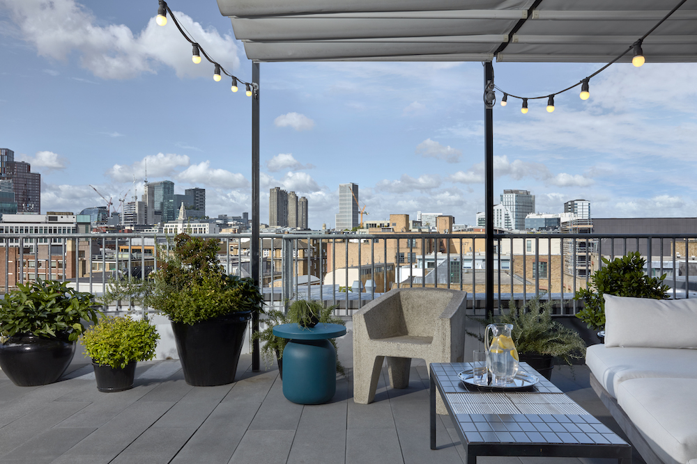 A balcony featuring white furniture, offering a scenic view of the city skyline in the background.