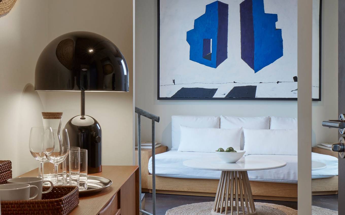 Close-up of a room setup with a sleek black lamp, glassware, and a bold blue abstract painting in the background.