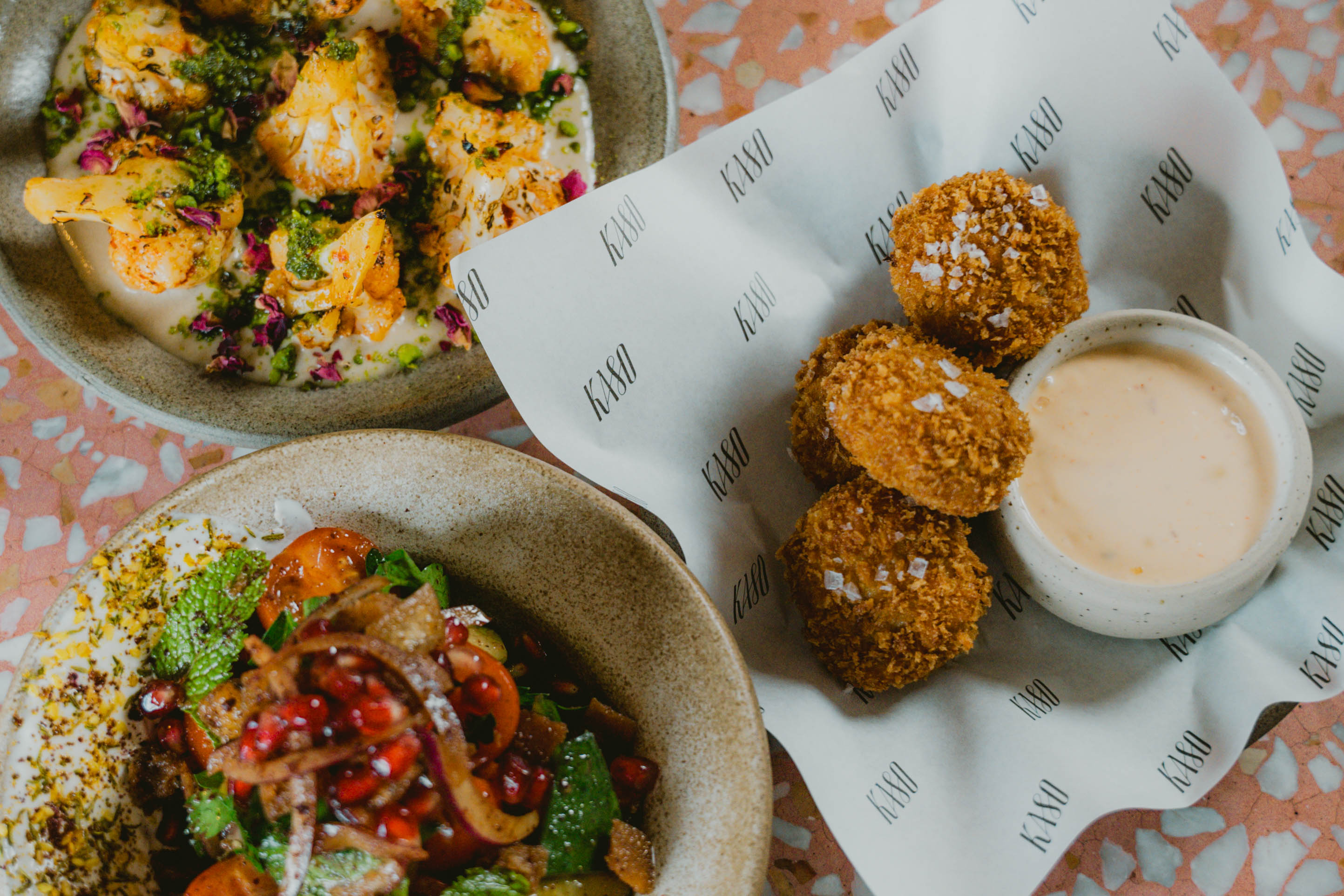 Crispy golden croquettes with flaky sea salt, served with a creamy dipping sauce alongside colourful salads at Kaso.