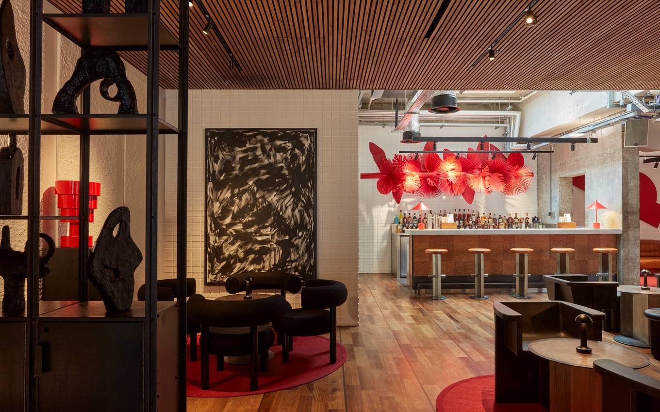 Modern London bar area with wooden floor, red decor accents, and artful lighting featuring abstract black and red wall art.
