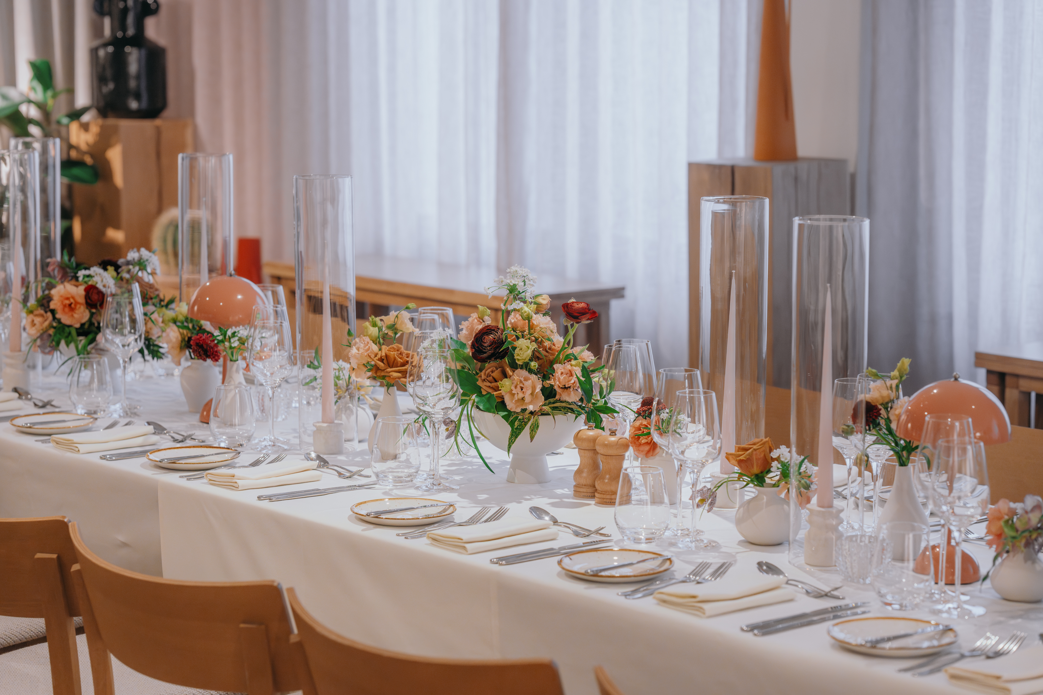 An elegant dining table with floral centrepieces, tall glass candles, and fine tableware, ready for a formal event in London.