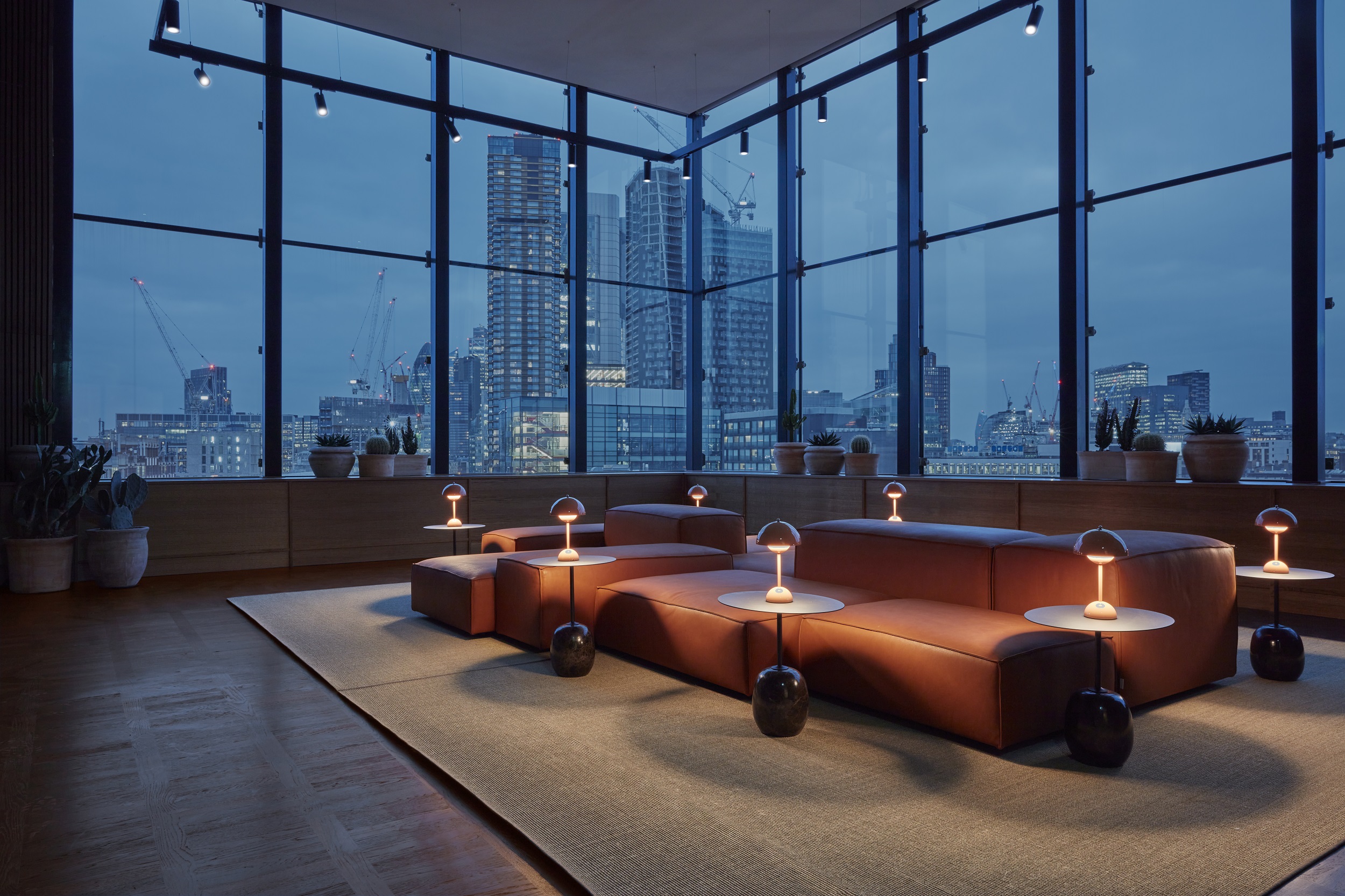 An elegant and cosy room featuring a stunning nighttime city skyline view through large windows.