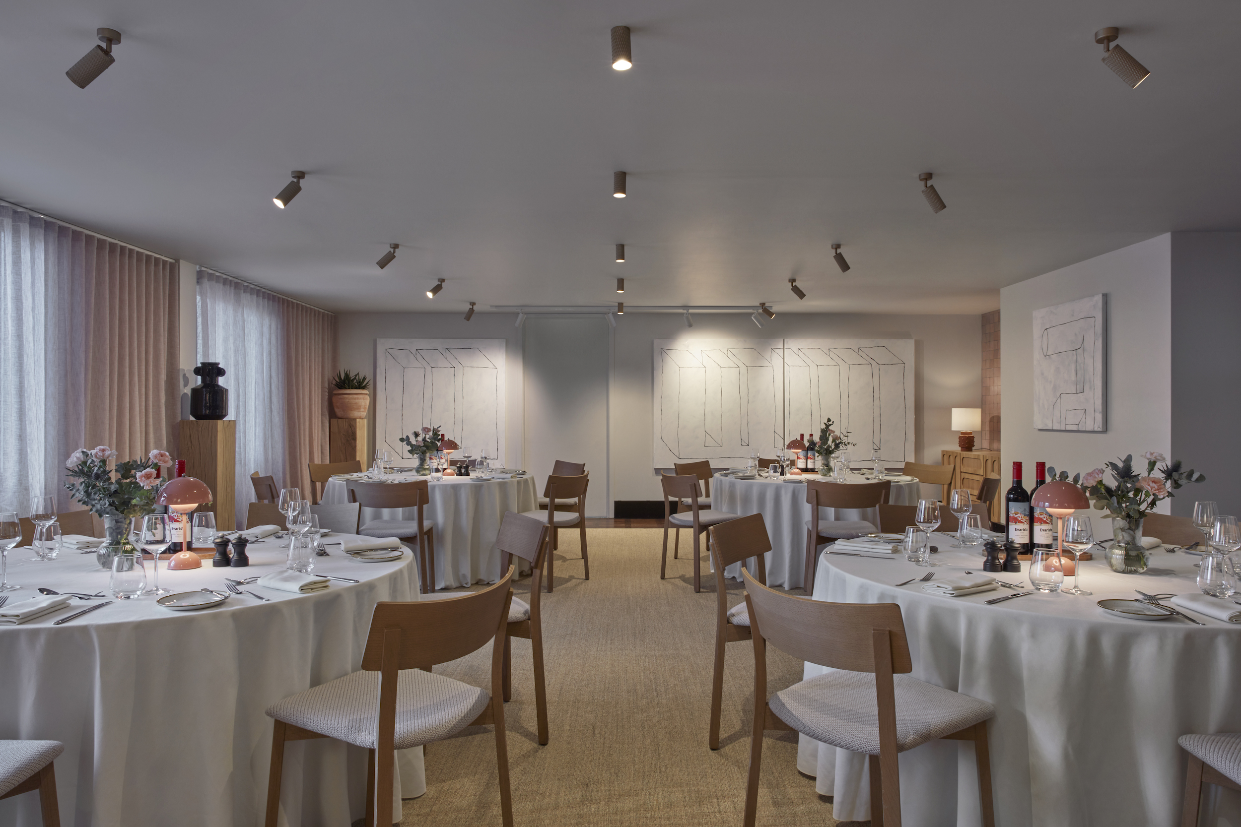 A spacious dining room arranged with tables and chairs, ready for an elegant dinner party setting.